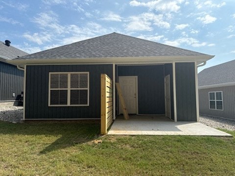 A small house with a grey roof and a grey exterior is shown with the door open.