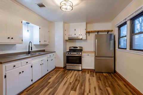 A kitchen with white cabinets and wooden floors.