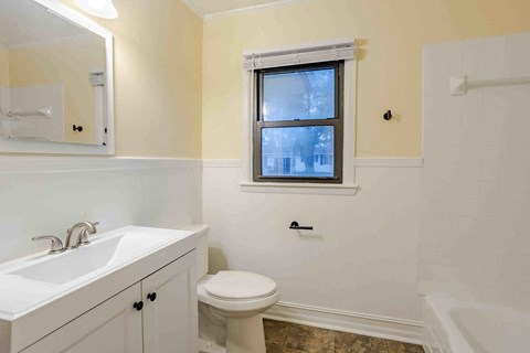 A bathroom with a toilet, sink, and tub.