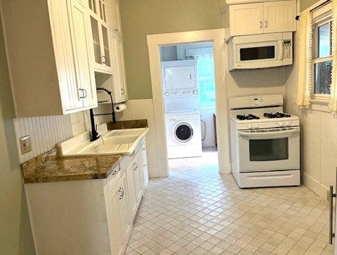 A kitchen with white cabinets and appliances.