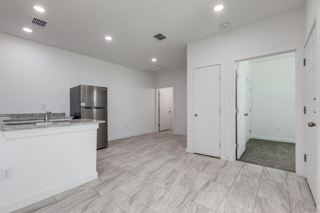 A kitchen with white cabinets and a marble countertop.