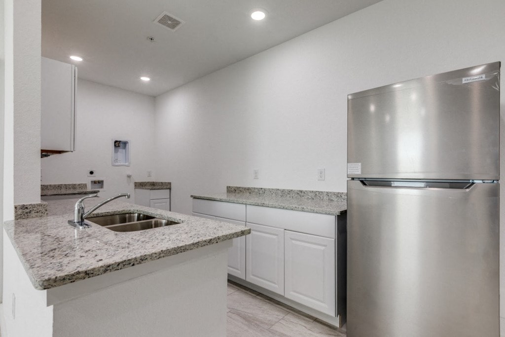 A modern kitchen with a stainless steel refrigerator and sink.