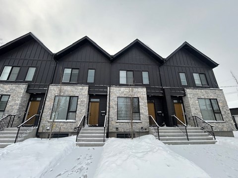 A black building with a snowy front yard.