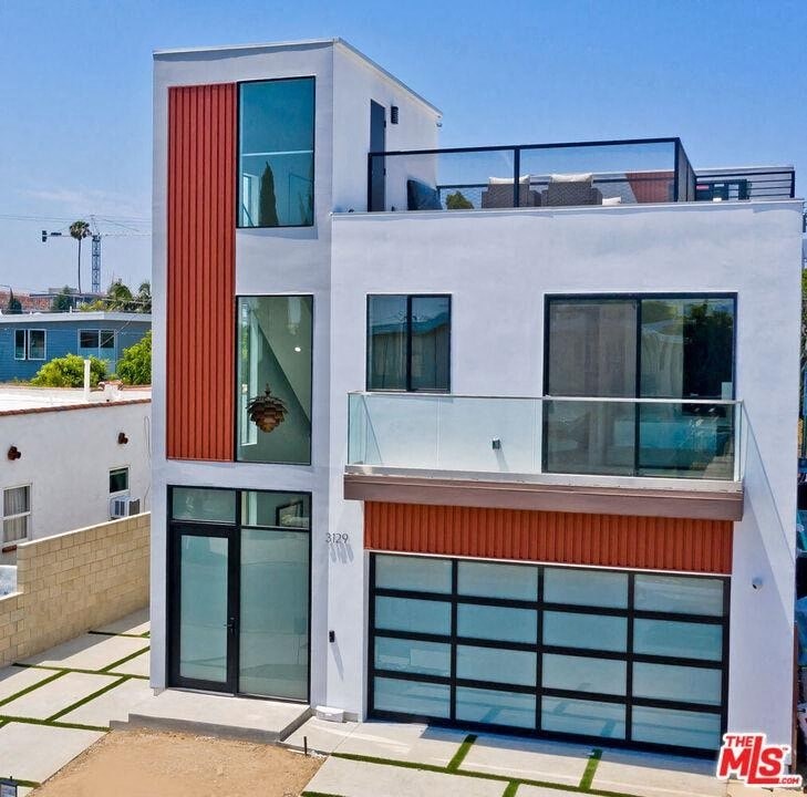 A modern two-story house with a balcony on the upper floor.