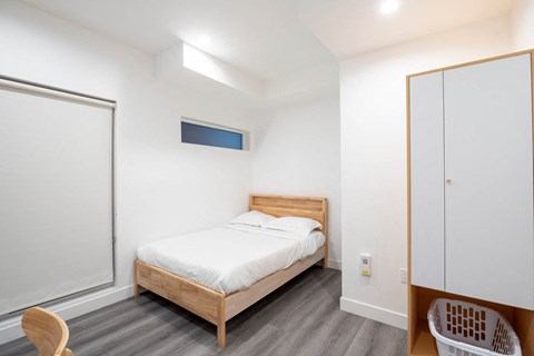 A bedroom with a bed, a chair, and a basket.