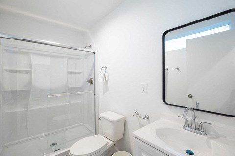 A white bathroom with a toilet, sink, and shower.