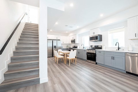 A modern kitchen with a staircase on the left side.