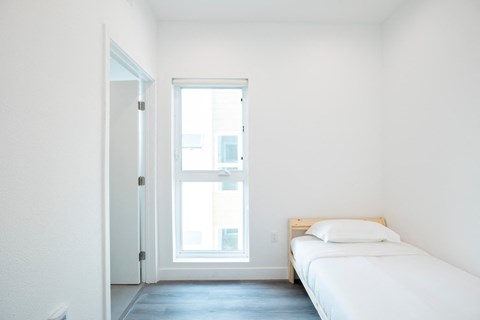 A white bedroom with a bed and a window.