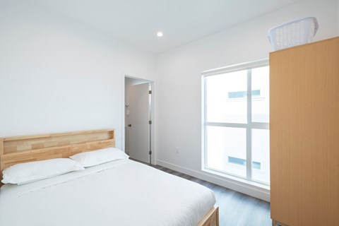 A bedroom with a bed, a dresser, and a window.