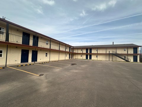 A large, empty parking lot in front of a building with multiple garage doors.