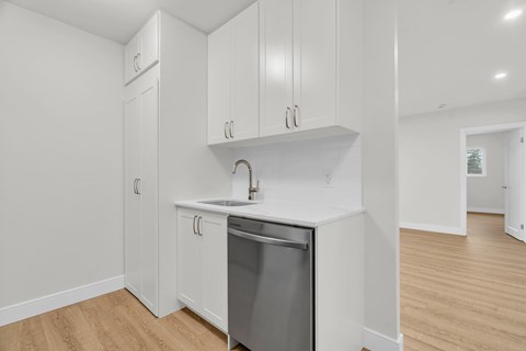 A kitchen with white cabinets and a dishwasher.