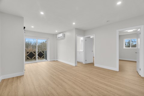 A spacious room with wooden flooring and white walls.