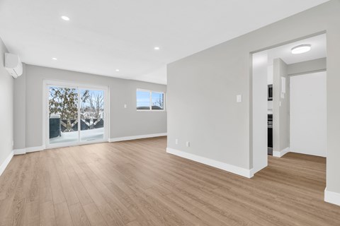 A spacious room with wooden flooring and white walls.