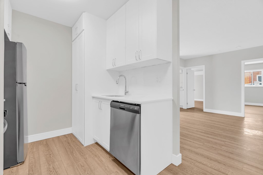 A kitchen with white cabinets and a stainless steel dishwasher.