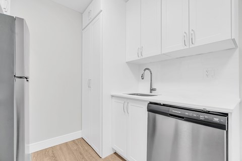 A kitchen with white cabinets and a stainless steel dishwasher.