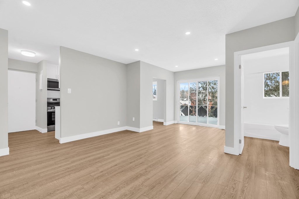 A spacious room with wooden flooring and white walls.