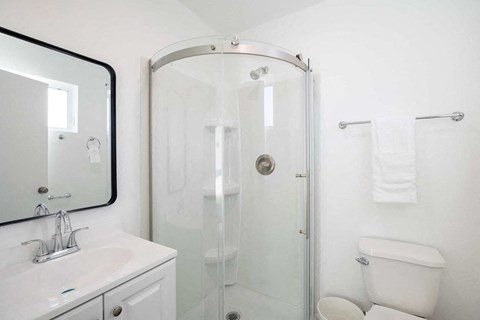 A white bathroom with a sink, toilet, and shower.
