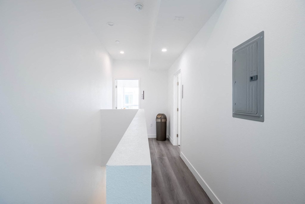 A long hallway with a trash can and a door on the right.