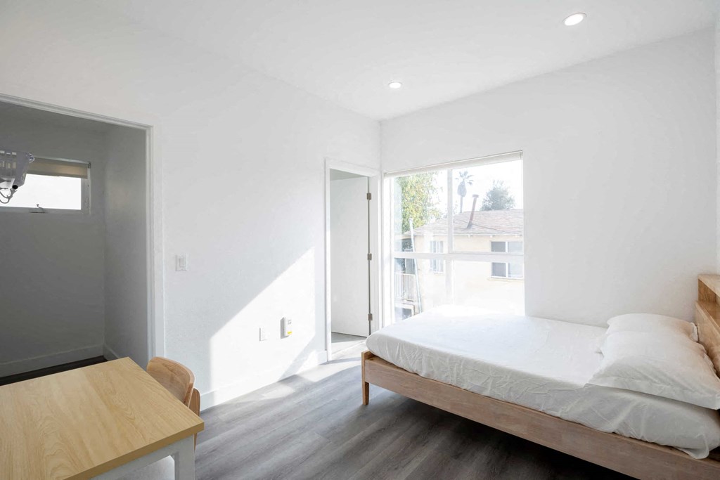 A bedroom with a bed, nightstand, and window.