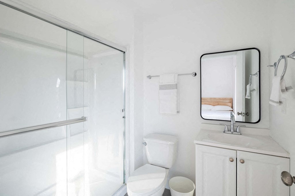 A white bathroom with a toilet, sink, and mirror.
