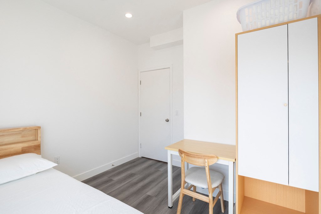 A bedroom with a bed, desk, and chair.