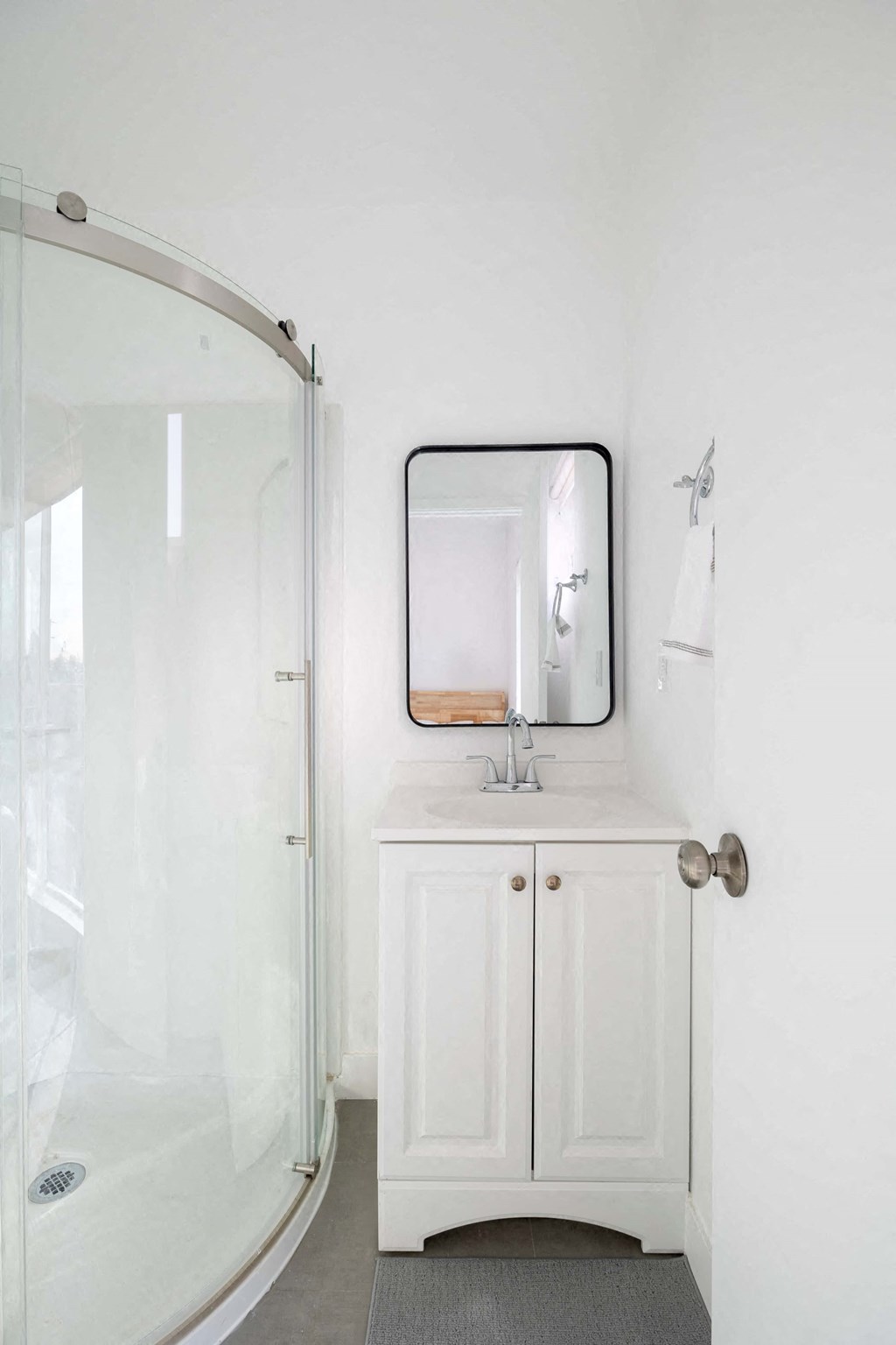 A white bathroom with a sink and a mirror.