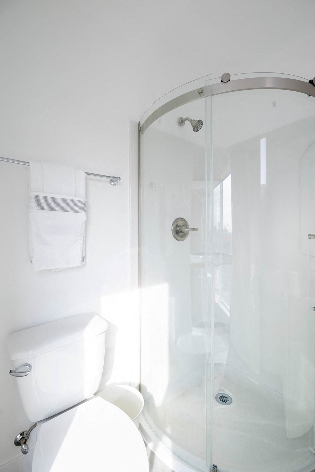 A white toilet with a glass shower door in a bathroom.