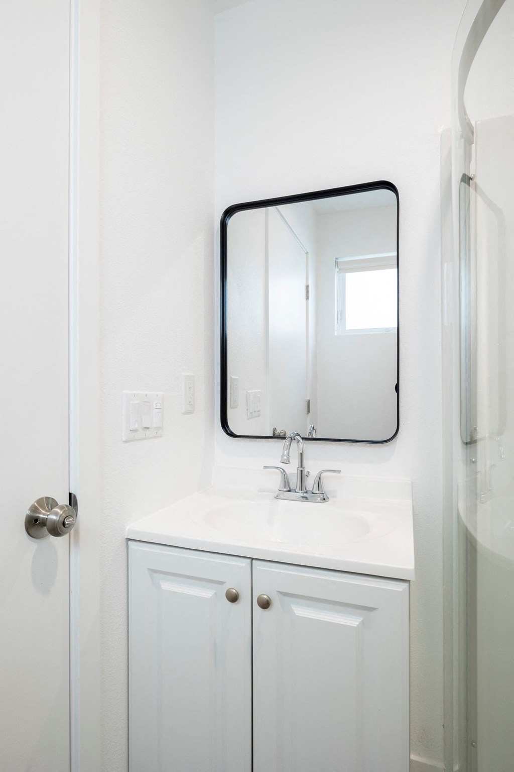 A white bathroom with a sink and mirror.