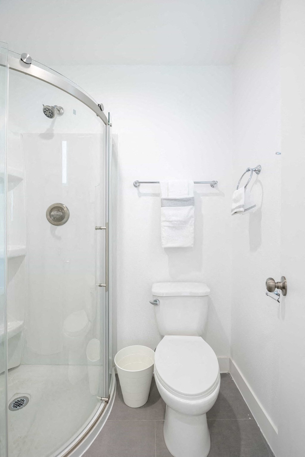 A white toilet sits next to a glass shower stall in a bathroom.