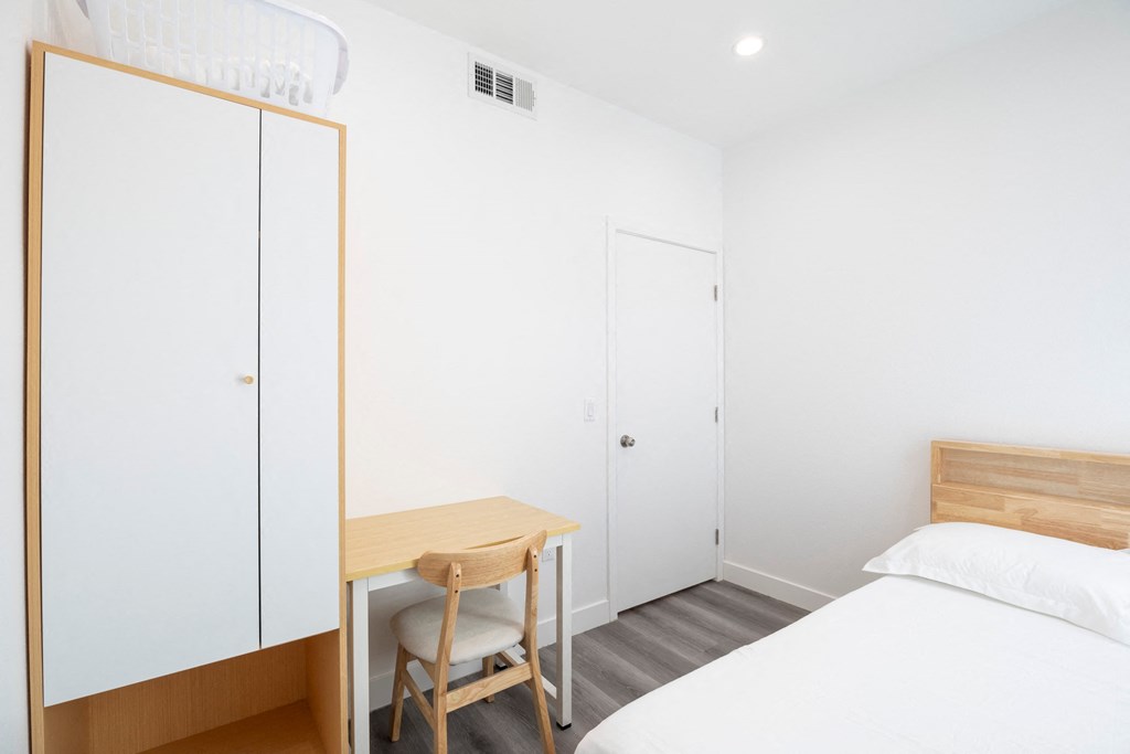 A bedroom with a bed, desk, and chair.