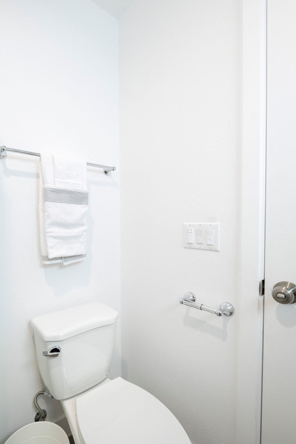 A white toilet with a towel rack above it.