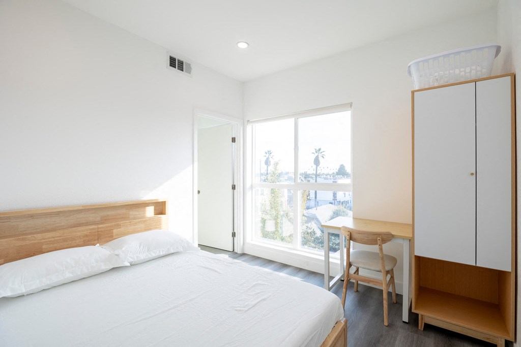 A bedroom with a bed, desk, and chair.