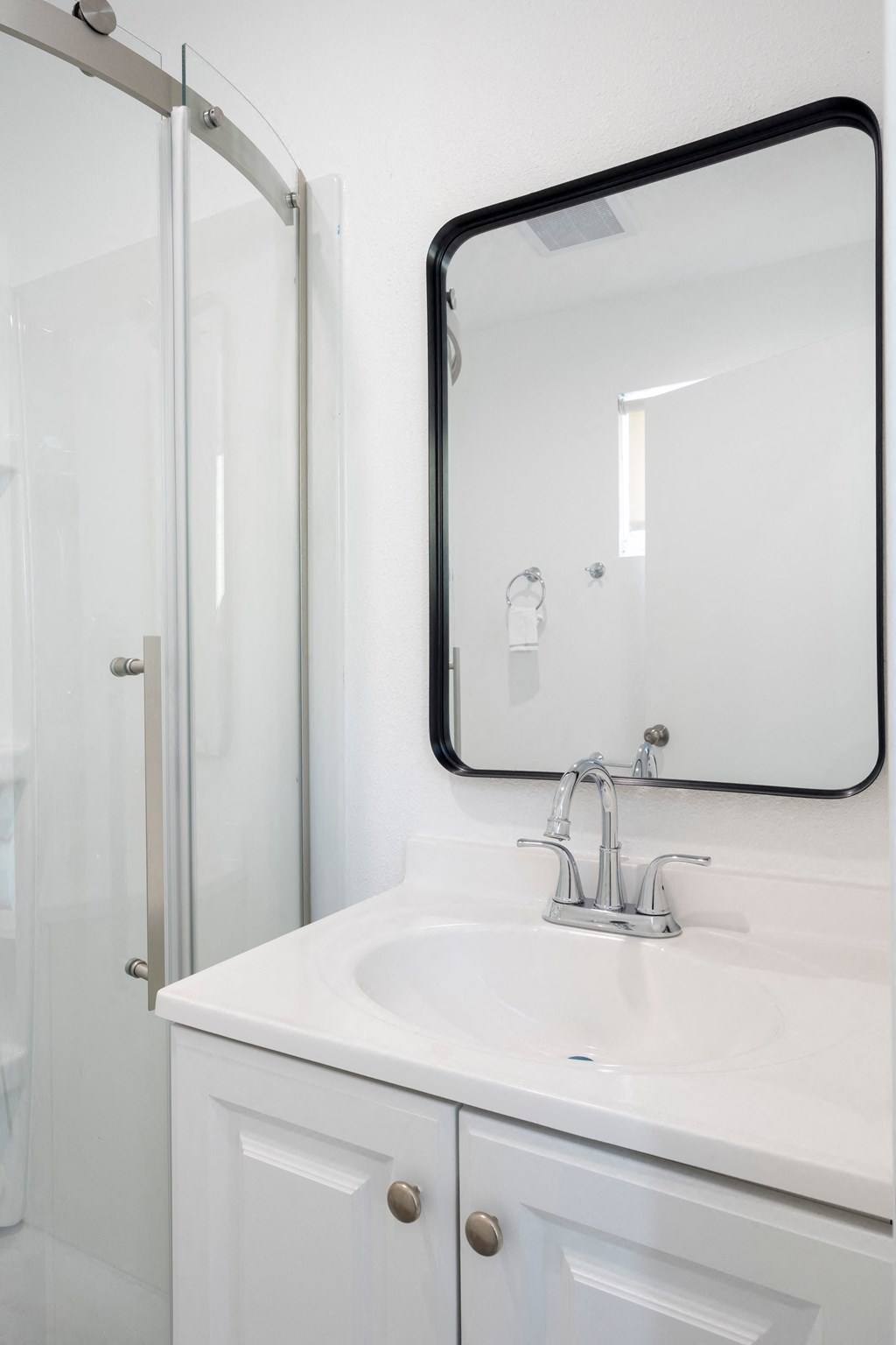 A white sink with a silver faucet and a mirror above it.