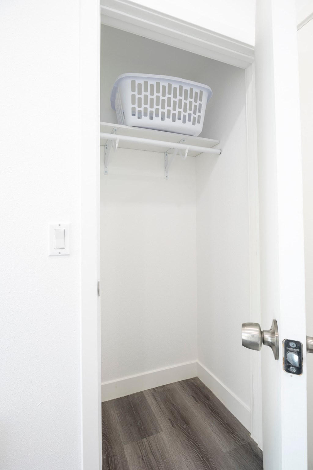 A white door with a silver handle and a white basket on top of a white shelf.