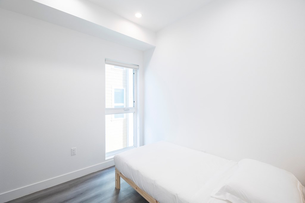 A white bed in a room with a window.
