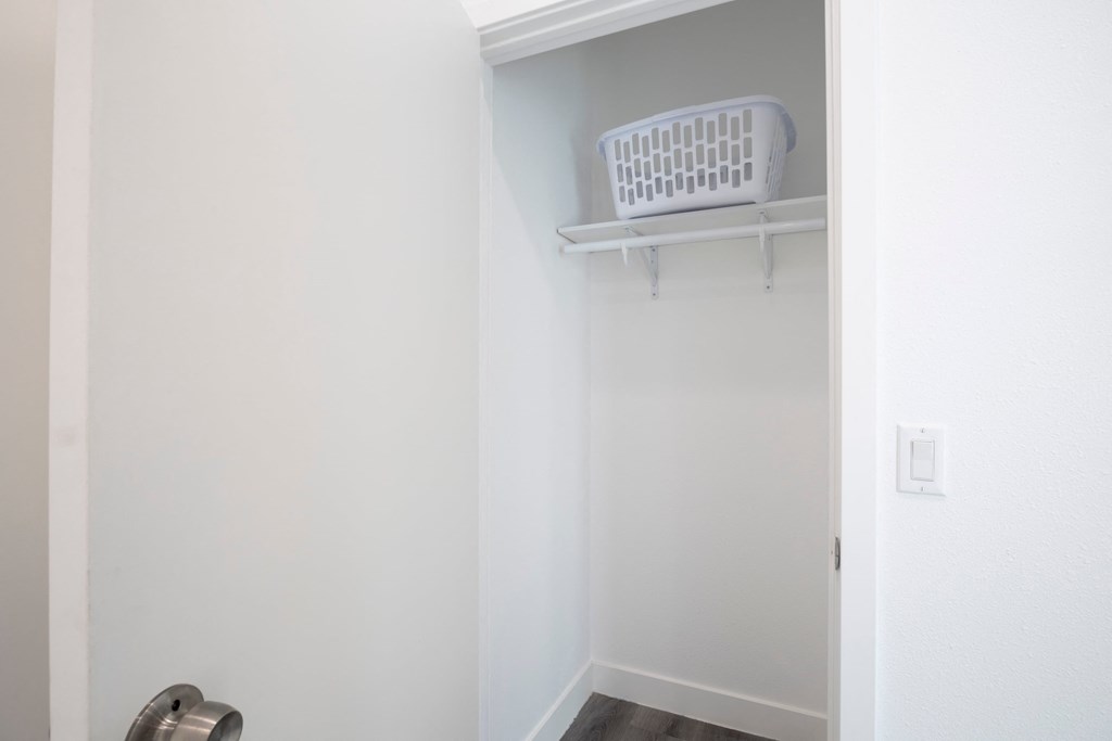 A white laundry basket hangs on a white door.