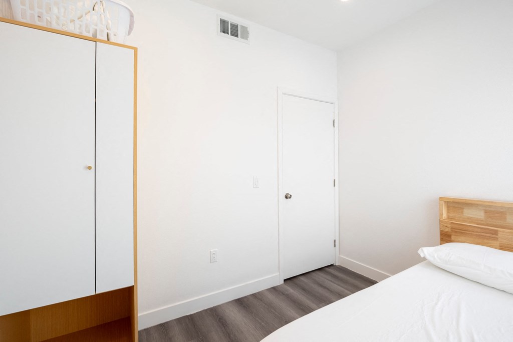 A bedroom with a bed, a dresser, and a wardrobe.