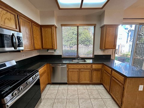 A kitchen with wooden cabinets and black countertops.