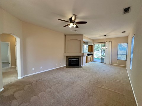 A living room with a fireplace and a ceiling fan.