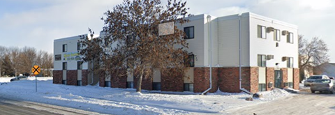 A white and brown building with a yellow sign in front of it.