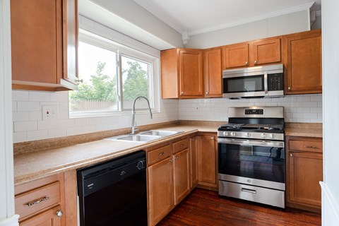 A kitchen with wooden cabinets and a black dishwasher.