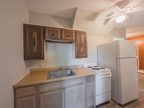 A kitchen with a white refrigerator, sink, and stove.