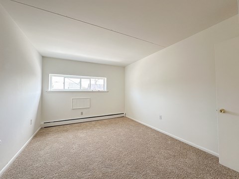 A room with two windows and a carpet on the floor.