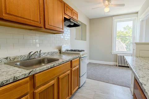 A kitchen with wooden cabinets and a marble countertop.