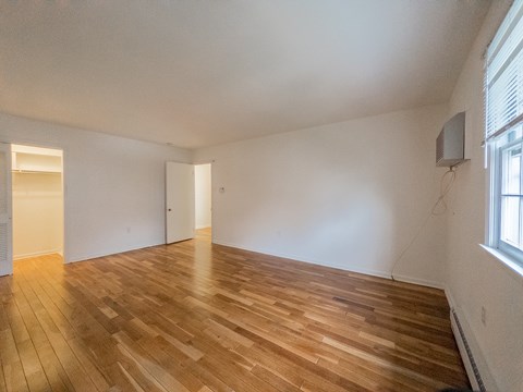 A room with wooden flooring and white walls.