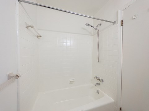 A white bathroom with a white tub and shower.