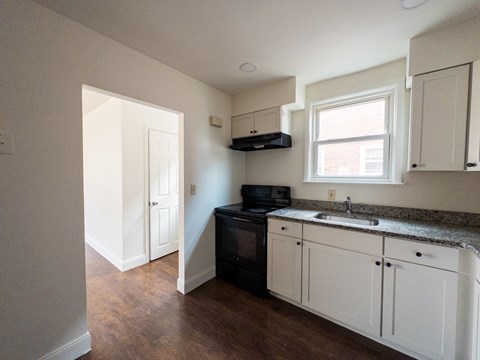 A kitchen with white cabinets and a black oven.