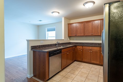 A kitchen with wooden cabinets and a black refrigerator.
