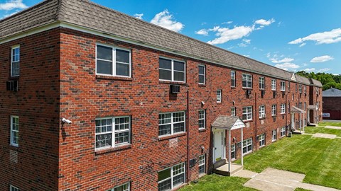 A large brick apartment building with a parking lot in front.