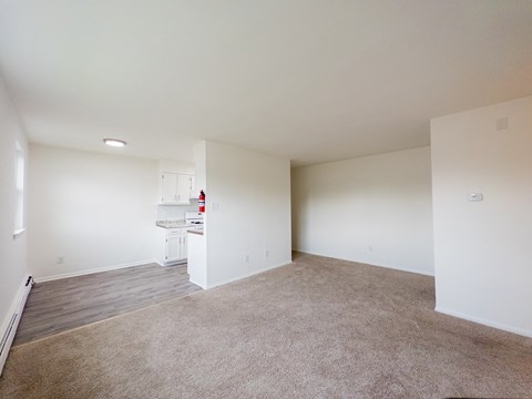 A large, empty room with a carpeted floor and white walls.